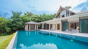Une maison moderne dotée d’une piscine, d’un patio couvert et d’un grand jardin.