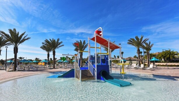 A water play area with slides and a climbing structure, surrounded by palm trees and beach chairs. - Luxury Villa in Orlando, Villa 1436 (Davenport)