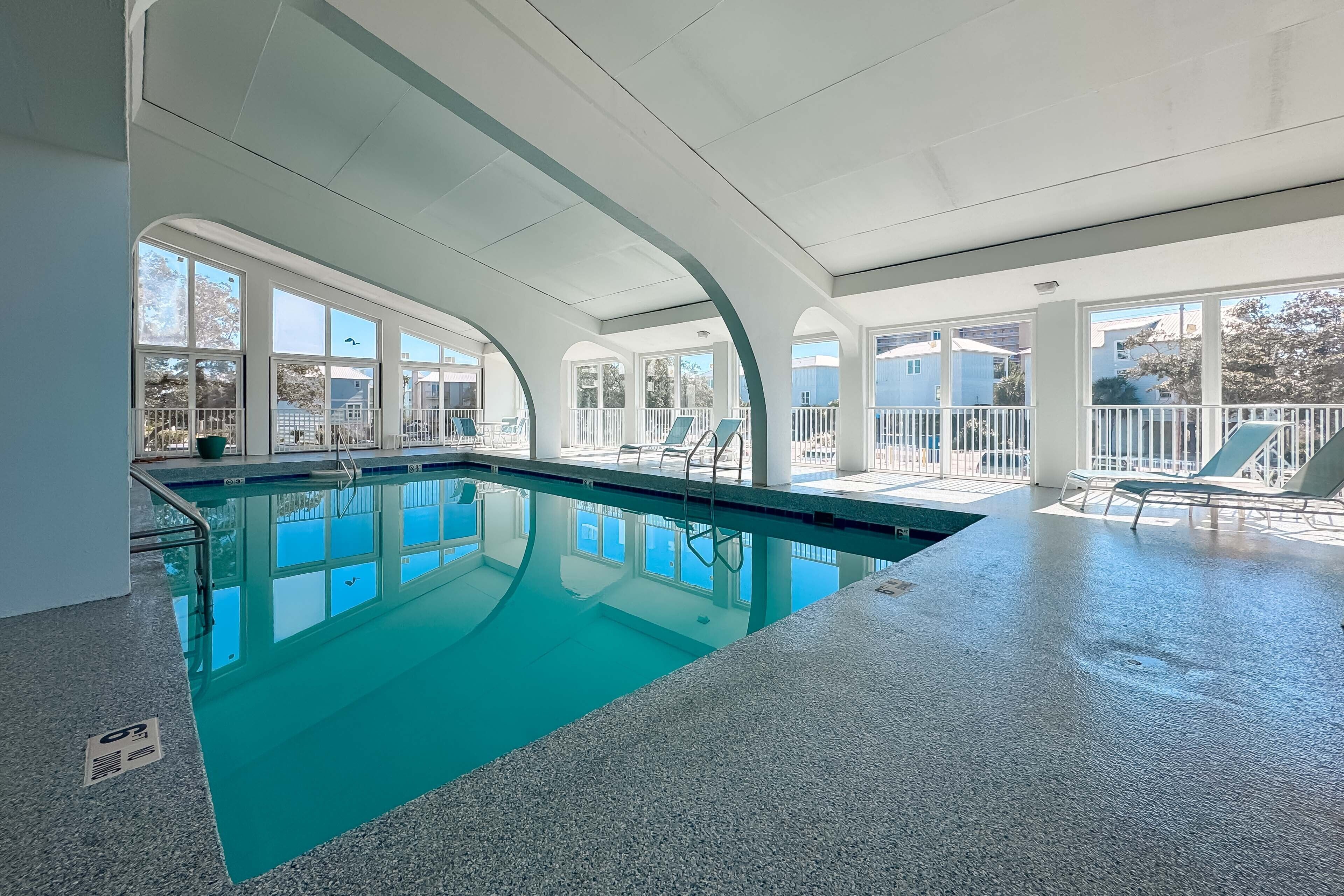 An indoor swimming pool with clear glass walls, a tiled floor, and a view of the outside.