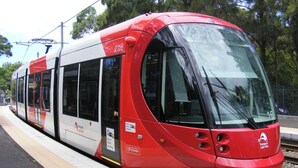 Een moderne tram met een rood-witte kleurstelling, nummer 2116, op een treinstationsperron.