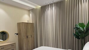 Une chambre à coucher avec un lit, une armoire en bois, un miroir et une plante.