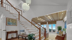Amplia sala de estar con escalera de madera, un ventanal con vistas y una zona de estar acogedora.