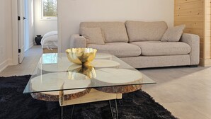 A modern living room with a glass coffee table, a beige sofa, and a wooden ceiling. - Moksa Spa Thermal Experience in Nature (L'Ange-Gardien)