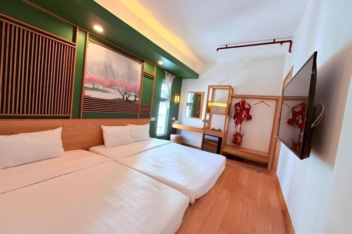 A hotel room with two beds, a painting, a mirror, and a television.