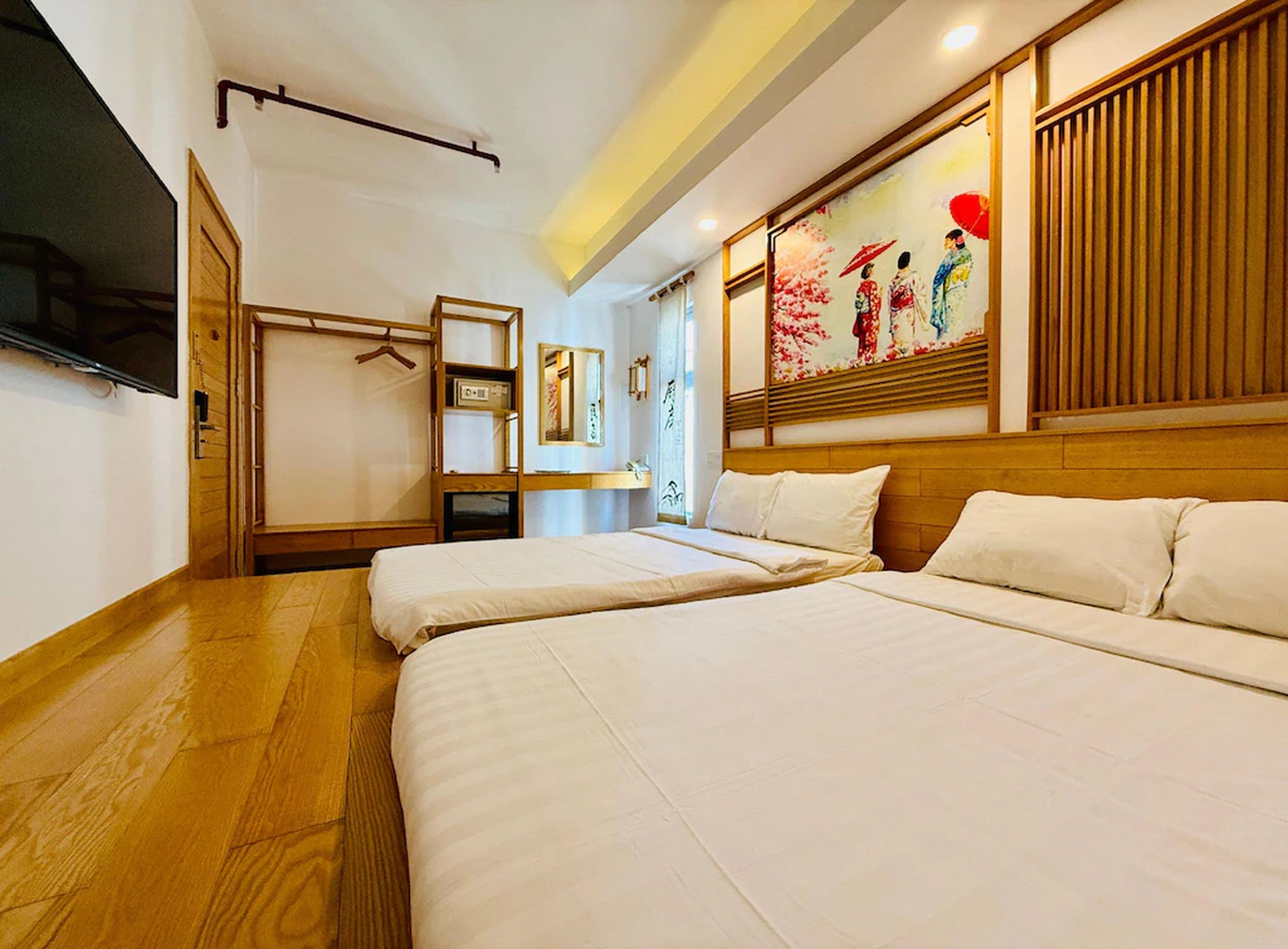 A hotel room with two beds, a TV, a wooden wardrobe, and a painting on the wall.