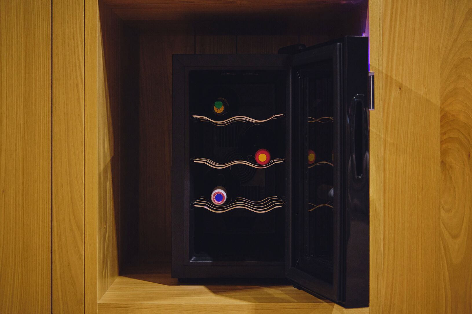 A wooden cabinet with a black interior, featuring three illuminated circular objects.