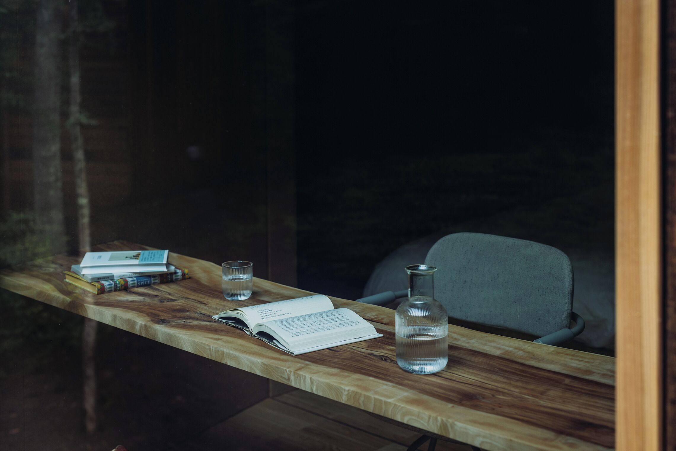 Una mesa de madera con un libro, un vaso y una botella.