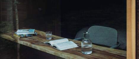 Una mesa de madera con un libro, un vaso y una botella.