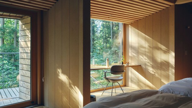 Une chambre avec une grande fenêtre, un plafond en bois et un lit.