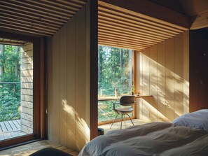 Camera da letto con una grande finestra, soffitto in legno e un letto.