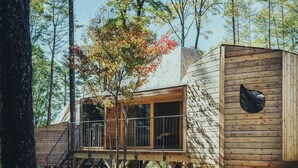 Une cabane en bois dotée d’un balcon, entourée d’arbres.