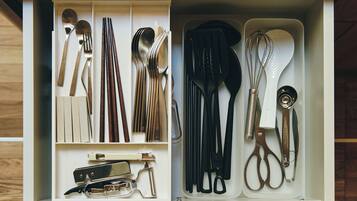 Un cajón con utensilios de cocina, incluyendo cucharas, tenedores, cuchillos y un batidor.