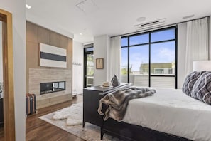 Quarto moderno com cama grande, lareira e vista exterior.