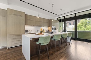 Uma cozinha moderna com uma ilha grande, banquetas e vista para o exterior.