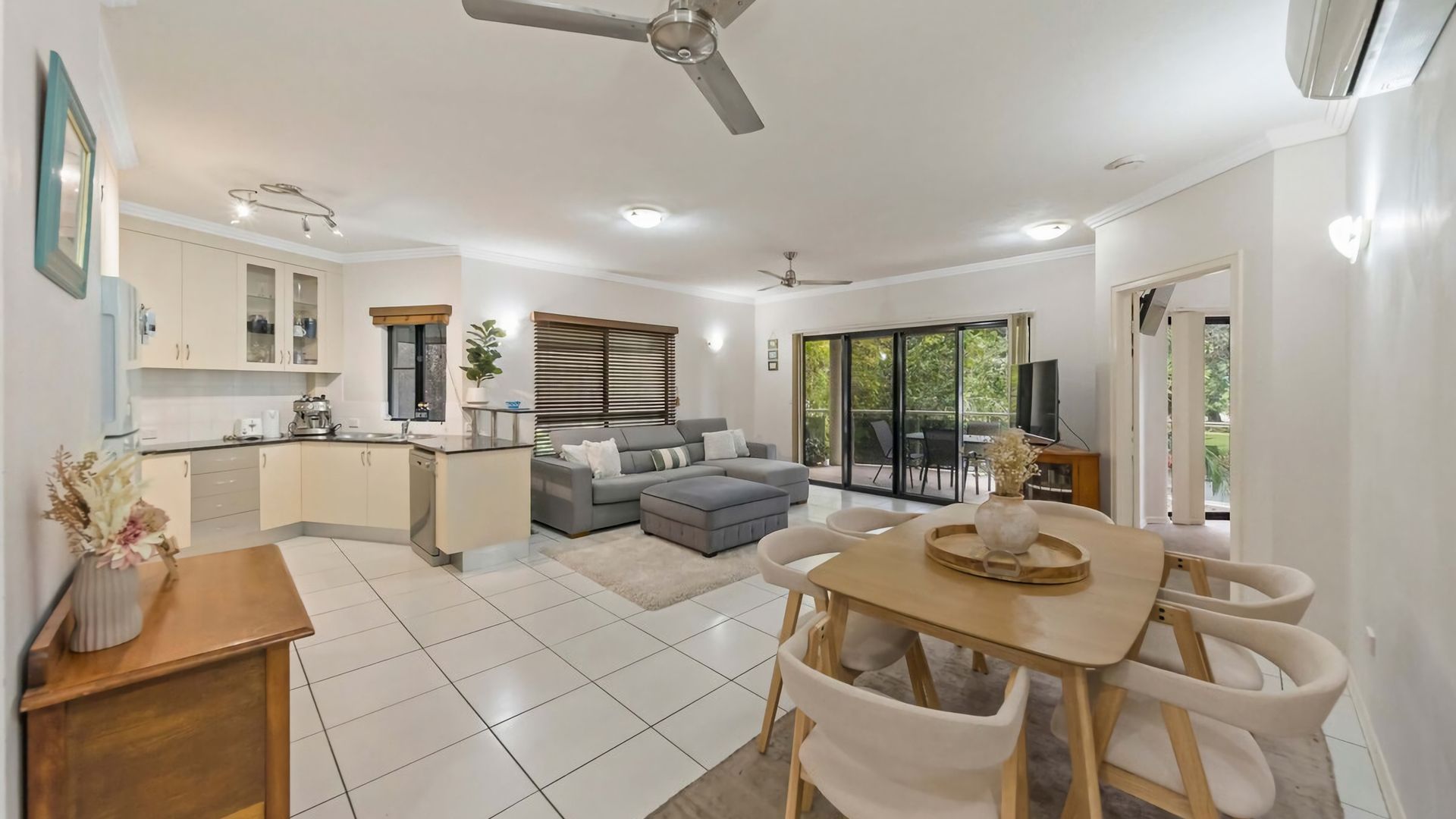 A modern kitchen with a dining area, a sofa, and a TV.