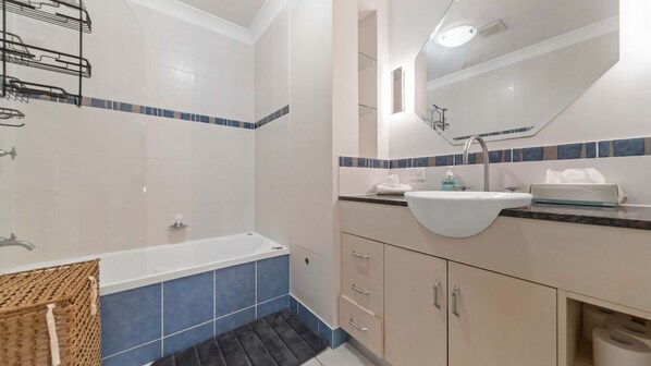 A modern bathroom with a bathtub, a sink, and a mirror.