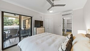 A bedroom with a bed, a television, a wardrobe, and a balcony with outdoor furniture.