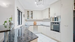 A modern kitchen with white cabinets, a granite countertop, and stainless steel appliances. - Beachside 2 bed 2 bath unit (North Ward)