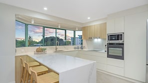 A modern kitchen with a large island, built-in appliances, and a view of the cityscape.