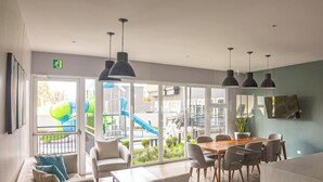 A modern kitchen with a dining area, large windows, and a view of a playground. - Volcano Views Luxury w/ KING Bed & Free Facilities (Guate)