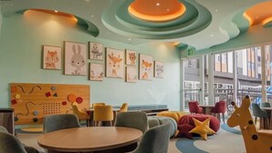 Un área de juegos para niños con muebles coloridos y decoración de pared con motivos de animales.