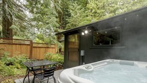 Un jacuzzi con panel de control, rodeado por una terraza de madera y una valla de madera.