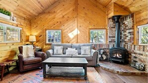 L’intérieur d’un chalet confortable, avec une cheminée, un canapé, une table basse et un tapis à motifs.
