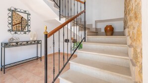 A staircase with a wooden handrail and black balusters, leading to a landing with a console table and decorative items.