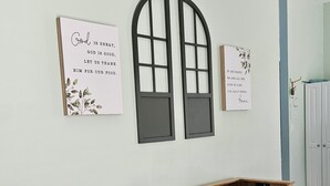 Ein Essbereich mit einem Holztisch, zwei Stühlen und zwei an der Wand befestigten Schildern mit religiösen Inschriften.
