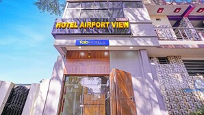 Een hotel genaamd "HOTEL AIRPORT VIEW" met een receptie en een bordje met de tekst "AC/ROOM".
