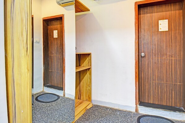 Un pasillo con puertas de madera, un pequeño estante de madera y un tapete de suelo estampado.