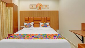 A hotel room with a large bed, a wooden headboard, and a bedside table.