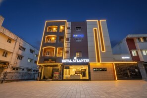 Een hotel genaamd "Royal Atlantis" met een modern design, dat een opvallende ingang en meerdere balkons heeft.