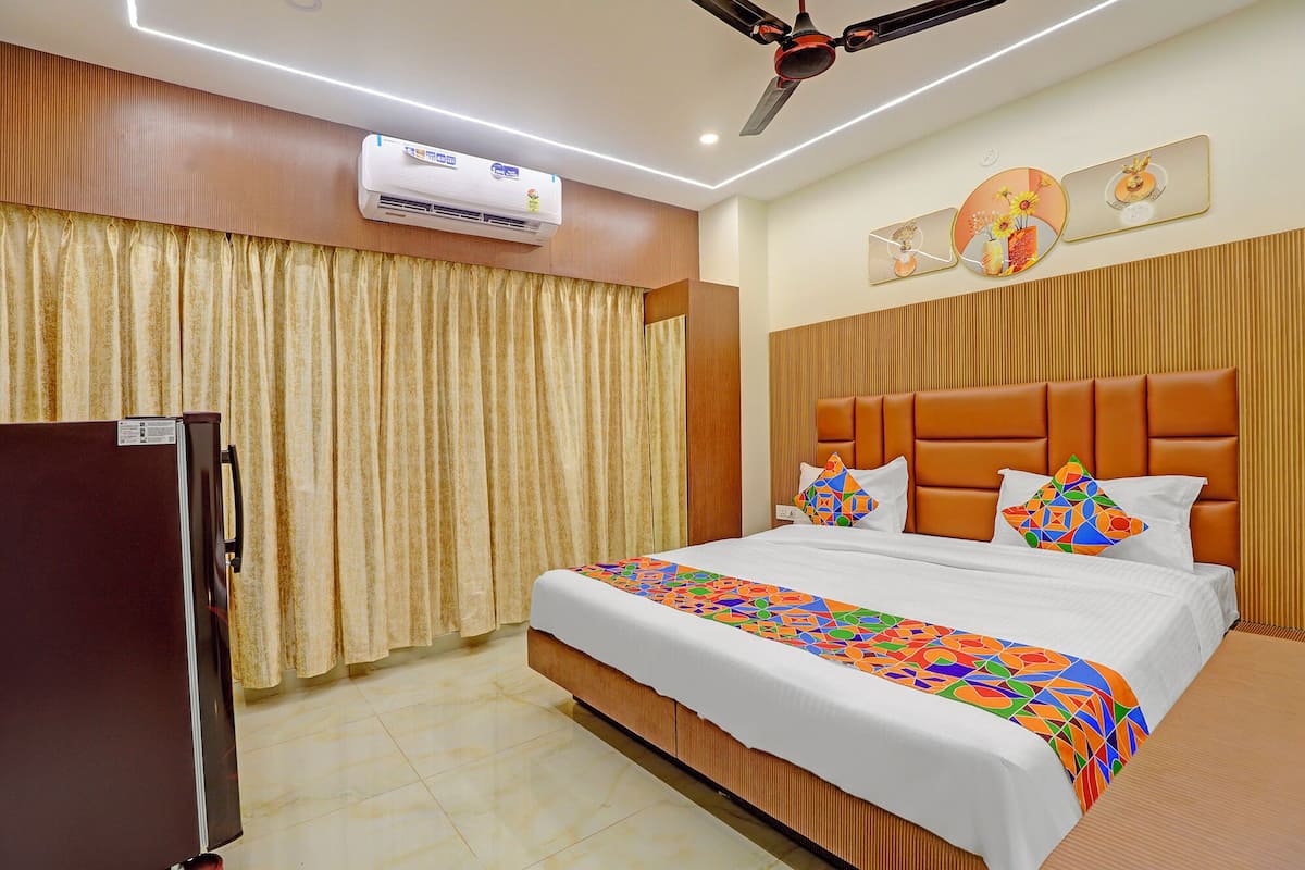 Une chambre d’hôtel équipée d’un lit, de rideaux, d’un climatiseur, d’un ventilateur de plafond et d’un réfrigérateur.