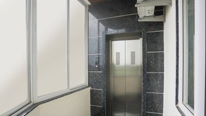 A narrow elevator with a digital display, flanked by walls with a marble-like finish and a window to the right. - Fabhotel Lake Vista (Indore)