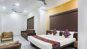 A hotel room with a large bed, a sofa, a chair, and a ceiling fan. - Fabhotel Lake Vista (Indore)