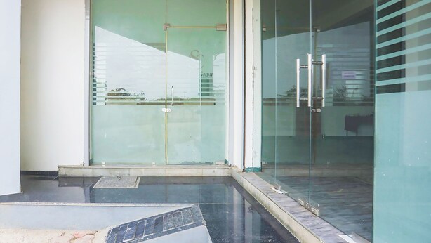 A modern building entrance with a glass door, a metal handle, and a small step leading up to the door. - Fabhotel Lake Vista (Indore)