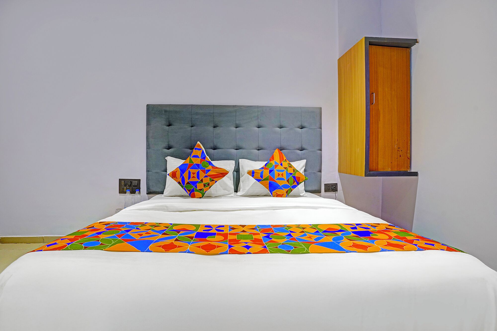 A bed with a colorful geometric-patterned bedspread and two pillows with a similar design.