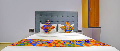 A bed with a colorful geometric-patterned bedspread and two pillows with a similar design.