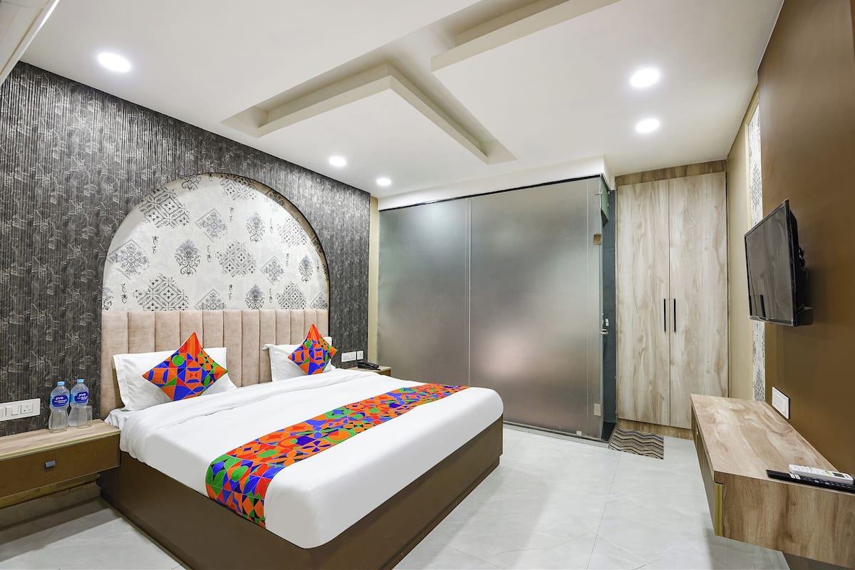 Een moderne hotelkamer met een groot bed, een garderobe, een televisie en een nachtkastje.