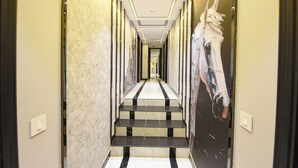 Een hotelhal met een marmeren vloer, een trap en een groot schilderij van een paard aan de muur.