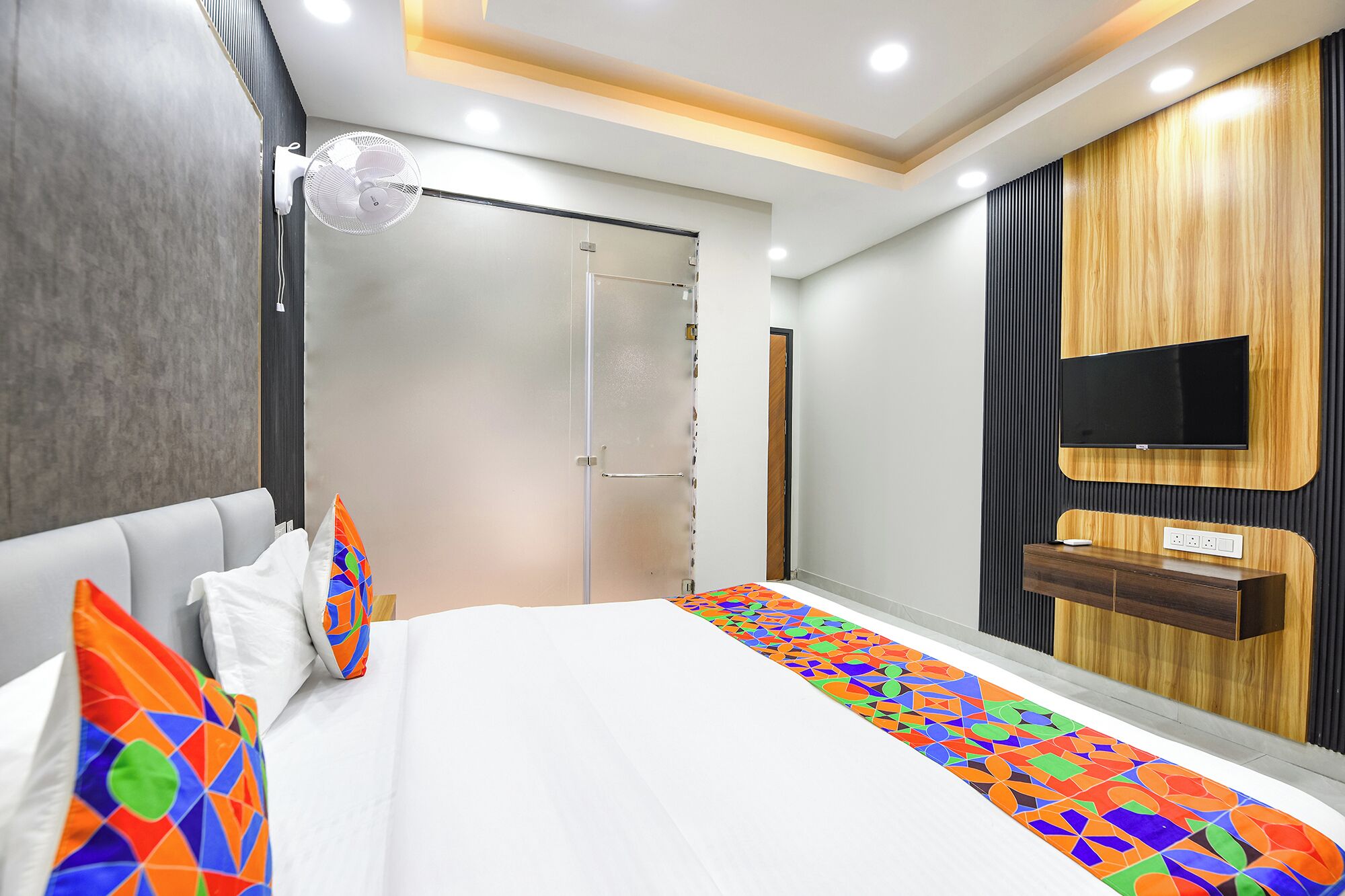 Ein modernes Hotelzimmer mit Bett, Fernseher und Schreibtisch.