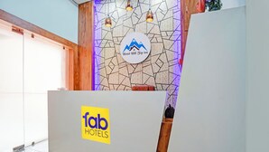 Ein Empfangsschalter mit dem Logo von 'Hotel Hill Top Inn' und einem Schild mit der Aufschrift 'fab HOTELS'.