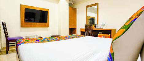 A hotel room with a bed, a desk, a chair, a television, and a mirror.