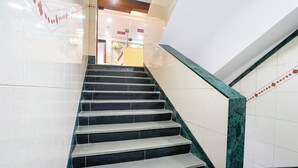 Una escalera con peldaños negros y barandillas de mármol verde que conduce a una zona de recepción.