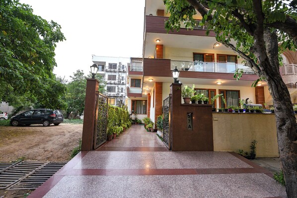 A multi-story building with a gated entrance, potted plants, and a paved pathway leading to the entrance. - FabHotel The Lalit Vibes - Nr. DLF Phase 2 & MG Road Metro (Gurugram)