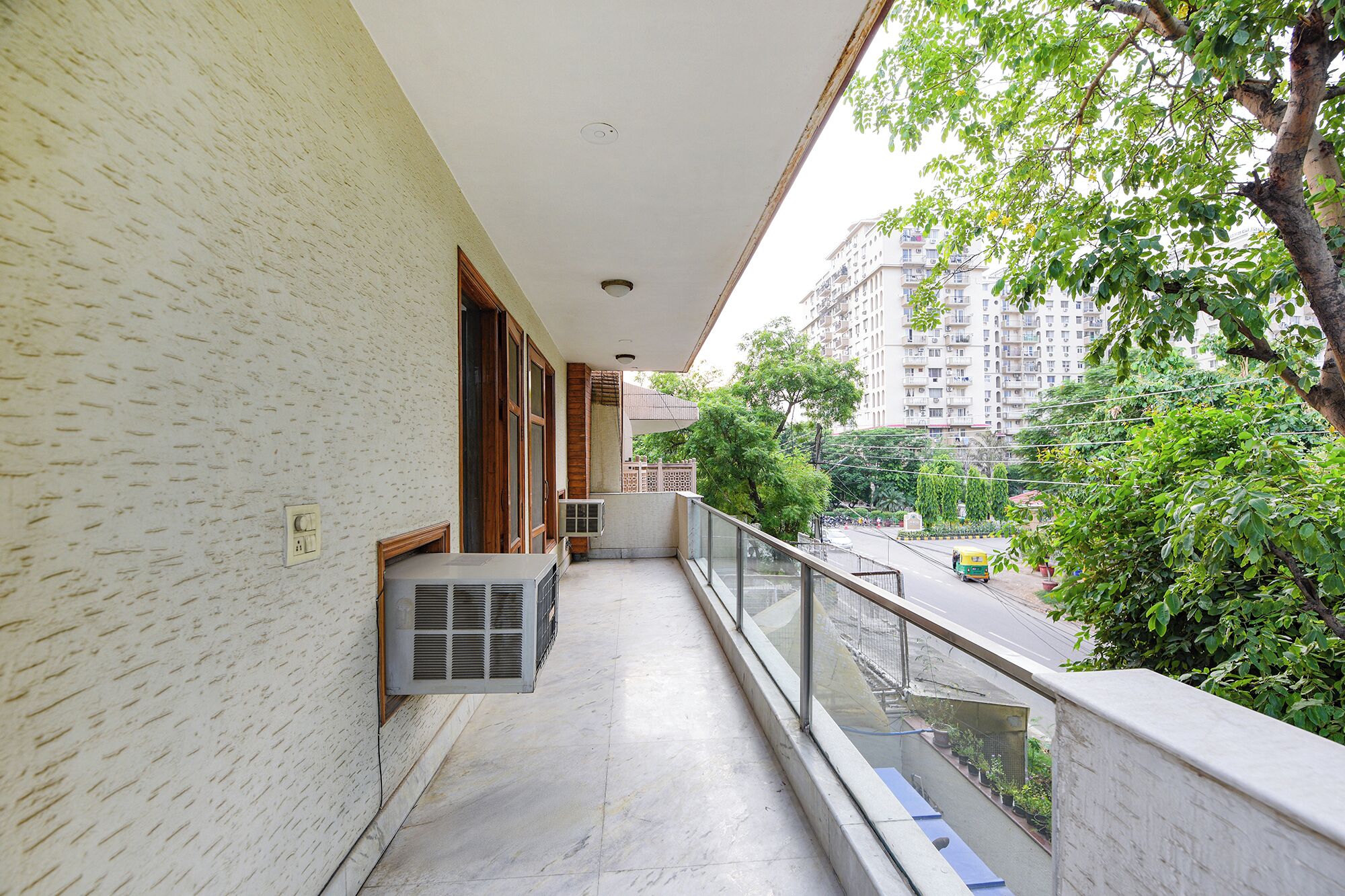 A balcony with a view of a cityscape, a tiled floor, and a window with blinds.