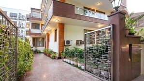 A modern residential building with a covered walkway, potted plants, and a decorative metal gate.