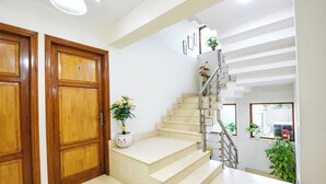 A staircase with a handrail, a potted plant on the landing, and a wooden door with a number.