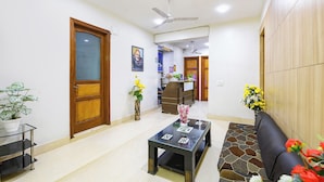 A reception area with a reception desk, a seating area with a sofa, a coffee table, and a potted plant.